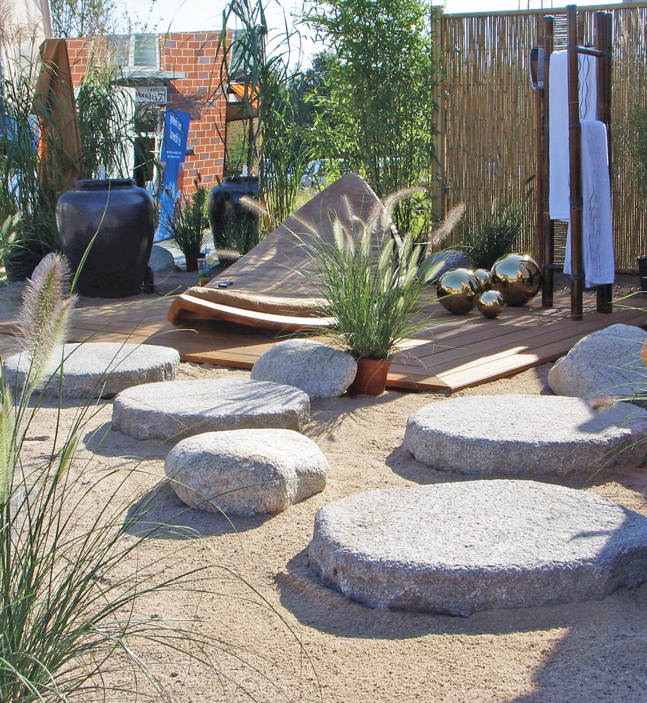 Reduzierter Garten mit Sand, großen Trittsteinen aus Granit und einer Lounge-Ecke.