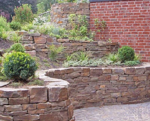 Naturstein Trockenmauer mit Terrassen für Pflanzen.