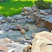 Ein kleiner mit Steinen geformter Bachlauf in einem Garten.