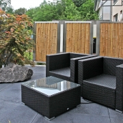 Bambussichtschutz auf einer Terrasse mit Loungegartenmöbeln davor.