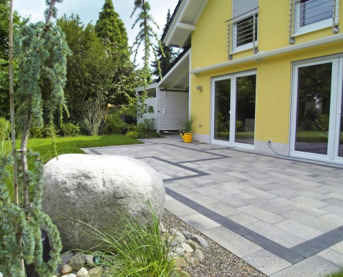 Formaler Garten durch ordnende Klarheit und Raumaufteilung durch eine Terrasse mit Bänderung und einem großen Findling.