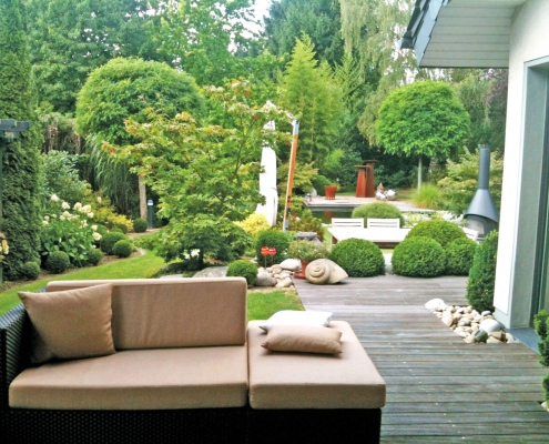 Loungecouch im Garten mit Blick auf ein sehr gelungenes Gartendesign.