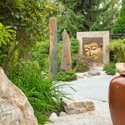 Japanischer Garten mit Bambus, Wasserspiel, Kies und einem Buddha Bildnis.