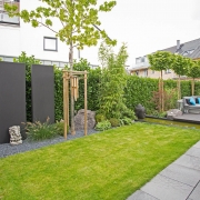Granit und Pflanzensichtschutz, Sitzgelegenheiten und eine kleiner Rasen in einem Garten in Bonn.