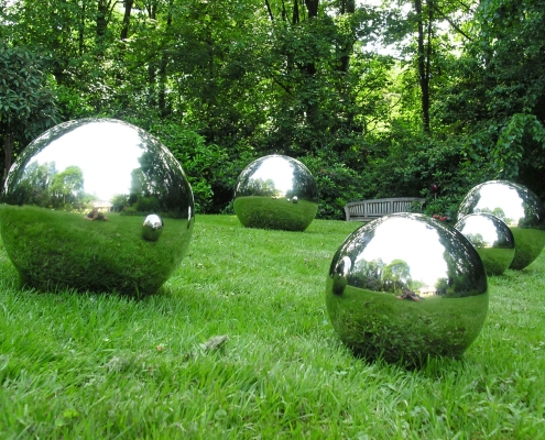 Glänzende Stahlkugeln auf weiter Grünfläche als Gartendesign.