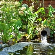 Wasser fließ aus einer Amphore in einen Gartenteich.