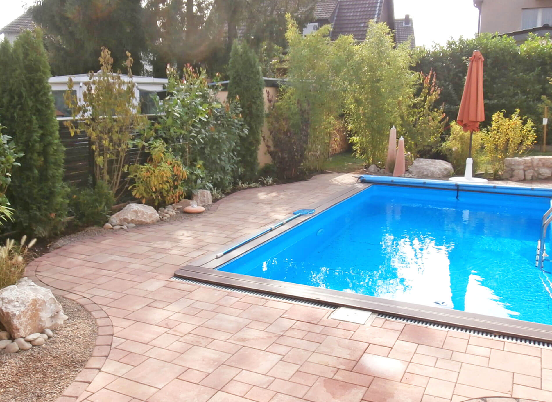 Schwimmbad im Garten mit Pflastersteinen und grüner Umrandung