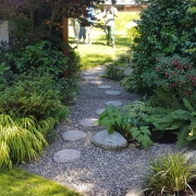 Trittsteine in Perlkies mit sehr schöner Bepflanzung zur Verbindung von zwei Gartenteilen.
