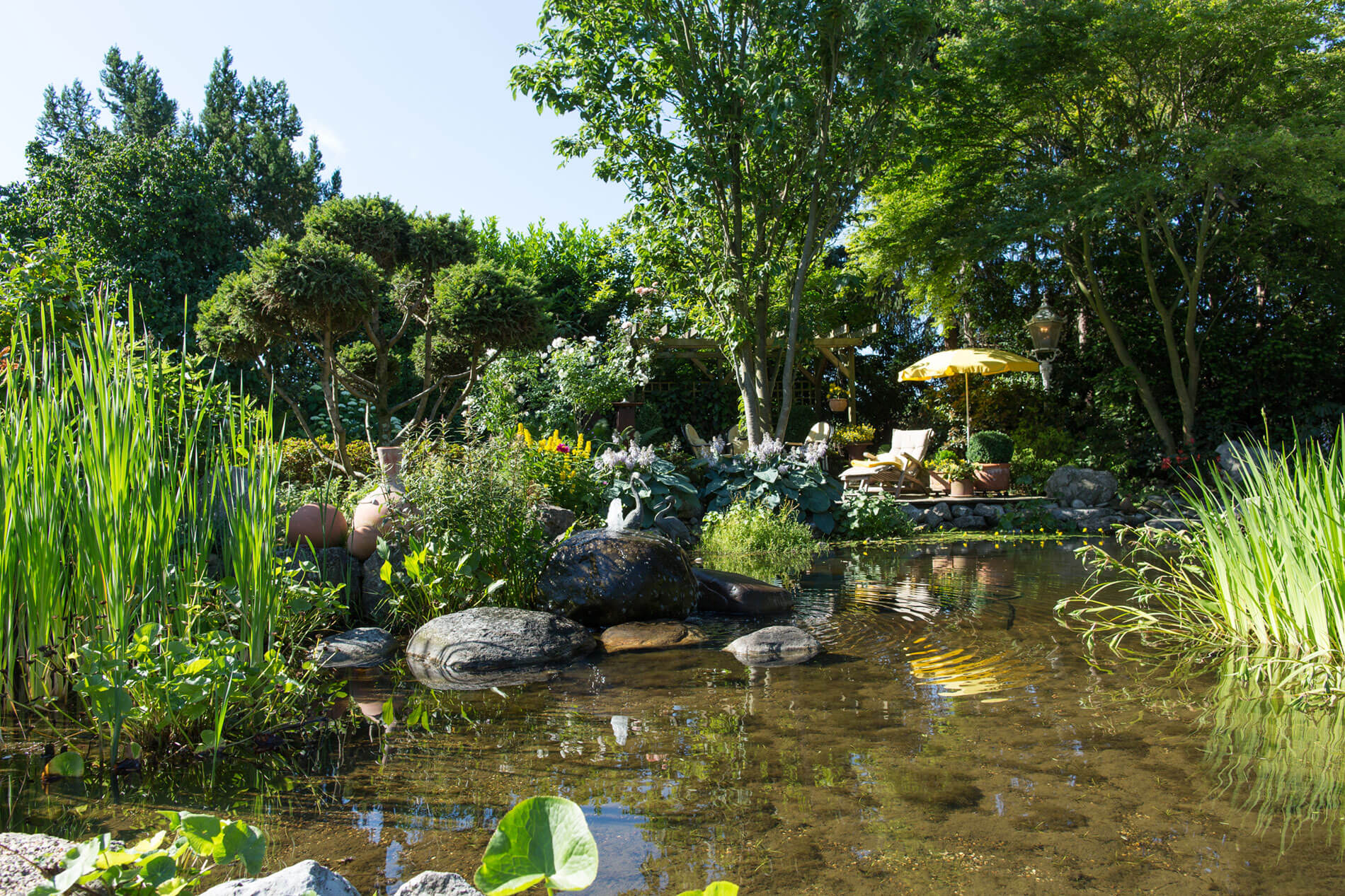 Eine sehr idyllisch angelegte Gartenlandschaft mit großem Teich von Gartendesign Wilczek